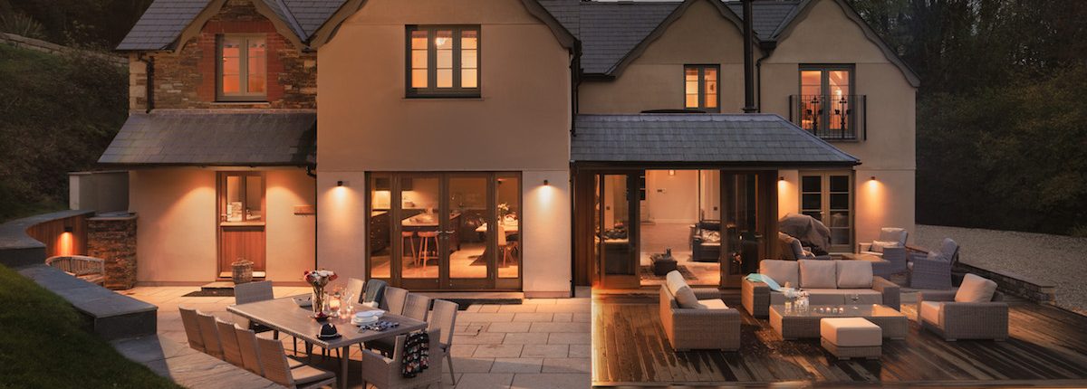 Rear view of the house at night with warm outdoor lighting and terraced seating areas
