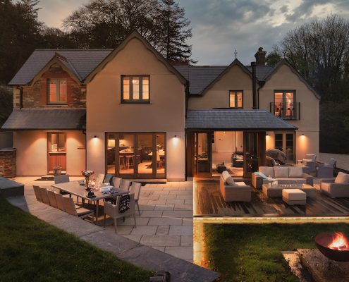 Rear view of the house at night with warm outdoor lighting and terraced seating areas