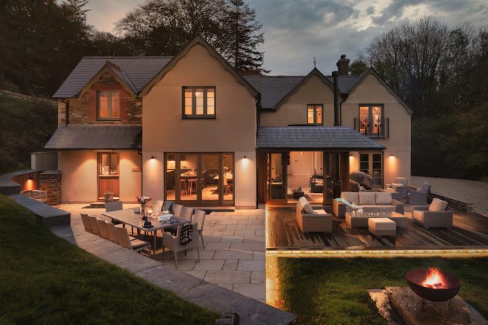 Rear view of the house at night with warm outdoor lighting and terraced seating areas